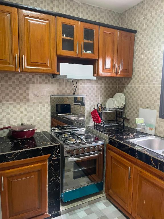 a kitchen with wooden cabinets and a stove top oven at Résidences Quezia in Libreville