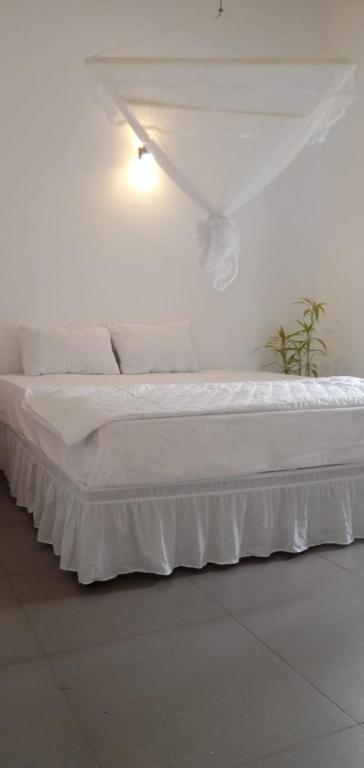 a white bed in a white room with a white canopy at 53 Villa in Habaraduwa Central