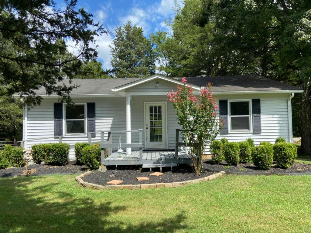 a white house with a bench in the front yard at Charming Country Cottage in Murfreesboro