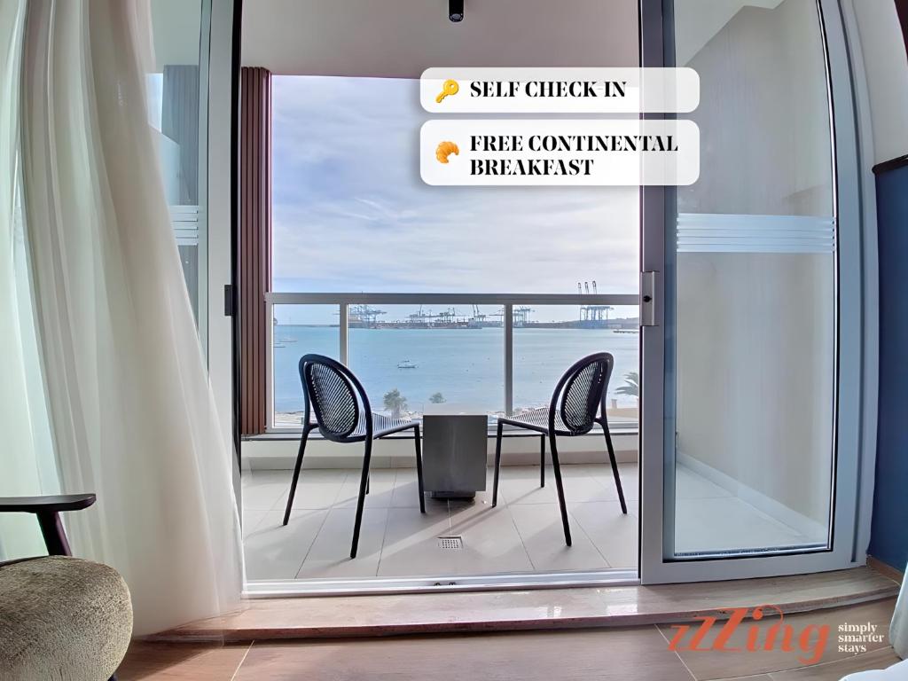 a table and chairs on a balcony with a view of the ocean at South 32 Hotel by Zzzing in Birżebbuġa