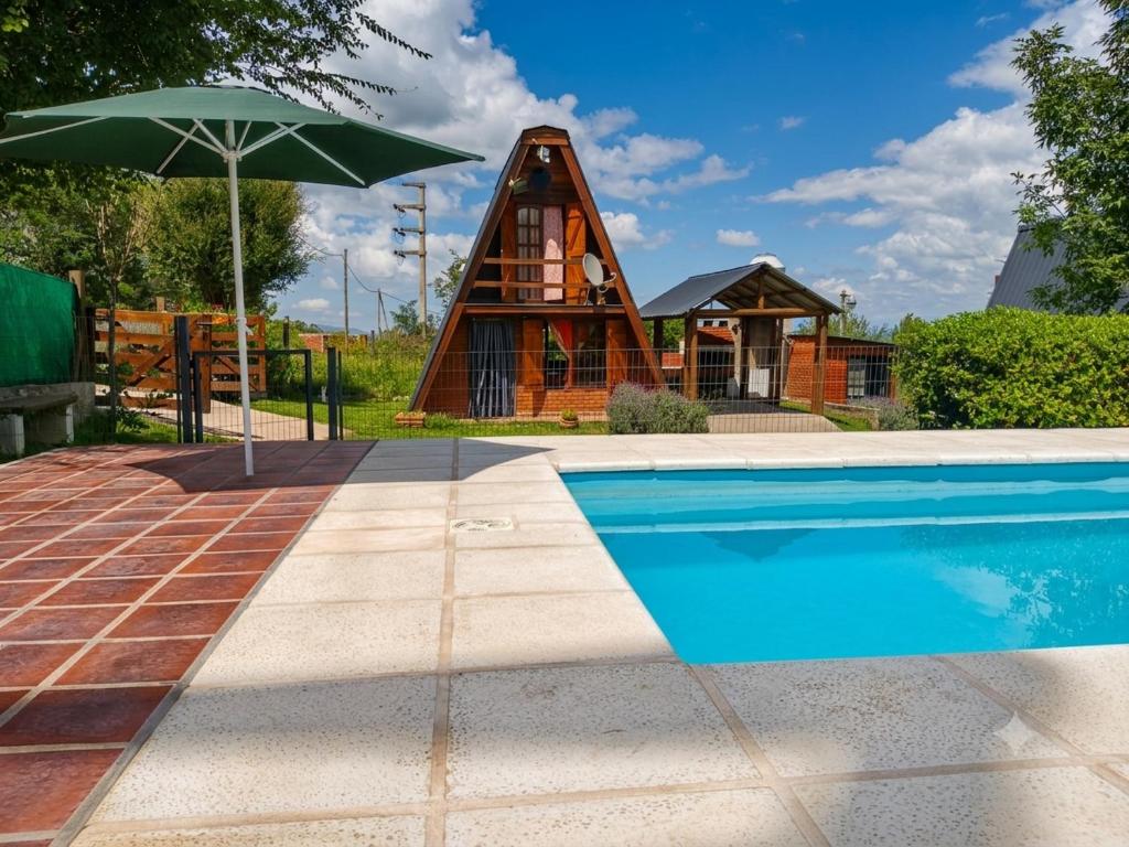 a house with a pool and an umbrella at Cabañas Don Luis in Valle Hermoso