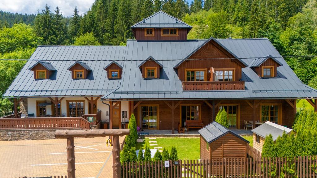 a large wooden house with a gambrel roof at Apartmány Jezerné in Velké Karlovice