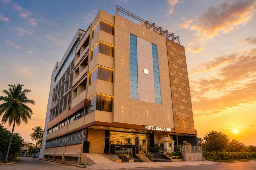 a hotel building with a sunset in the background at Hotel RAAGA INN in Tirupati
