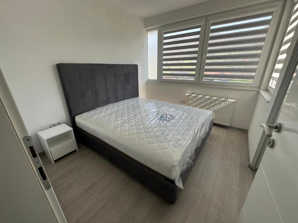 a bedroom with a bed in a room with windows at Apartment Eneya in Pazarić