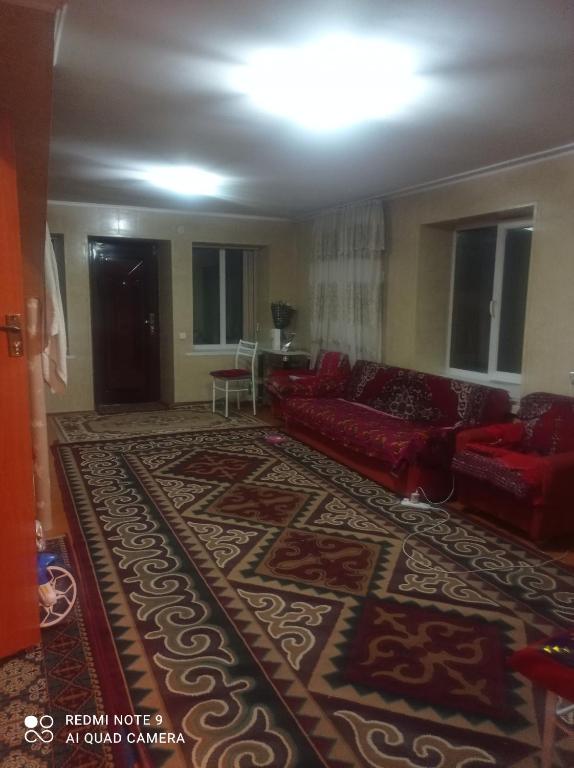 a living room with a red couch and a rug at Izat in Karakol