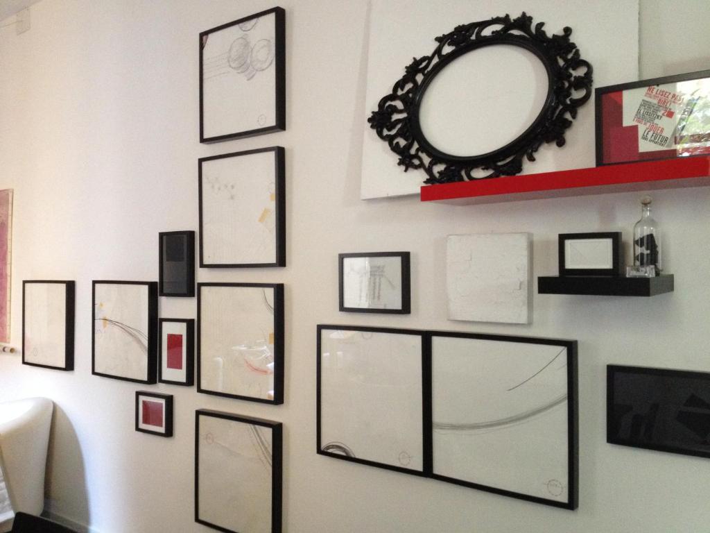 a wall full of pictures on a wall with a mirror at Mars41 B&B in Bologna