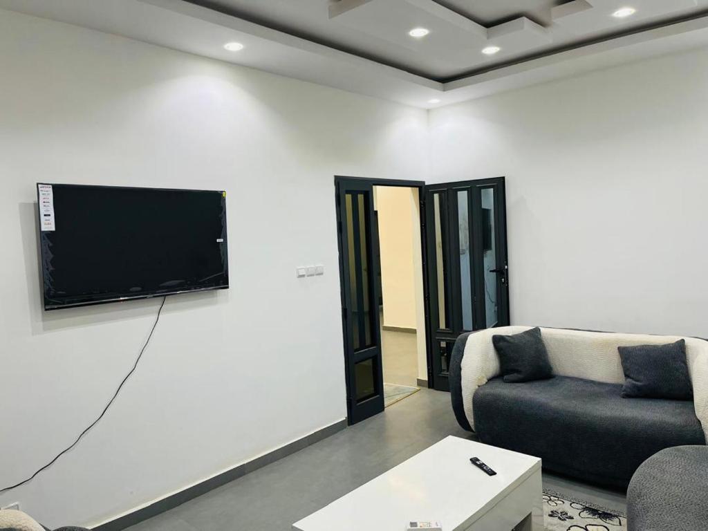 a living room with a couch and a tv on a wall at L'évasion-Royale in Thiès