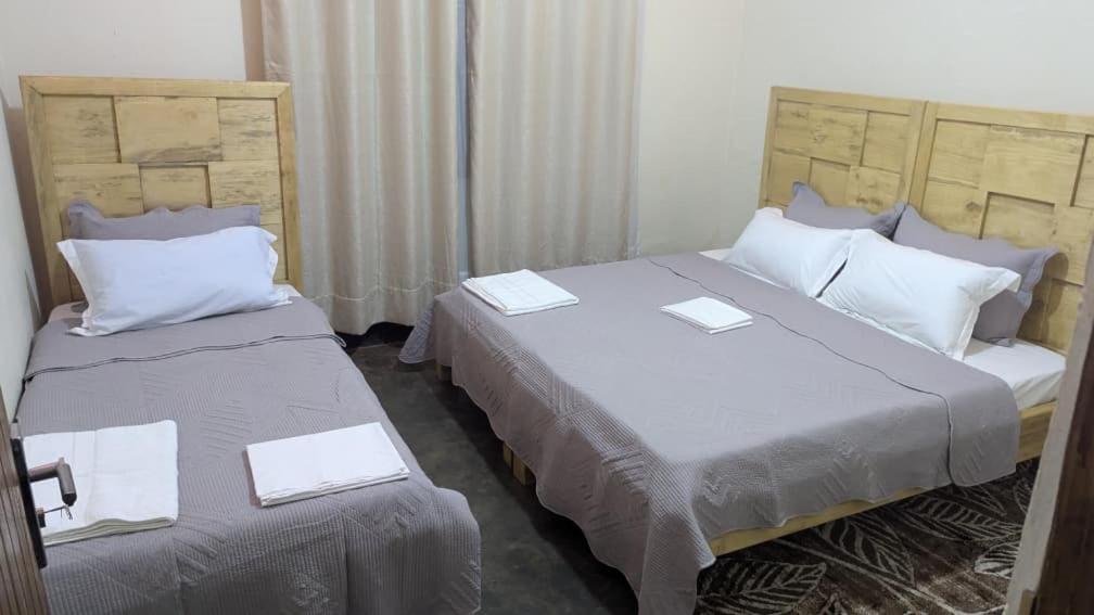 two beds in a hotel room with two at CJ Apartments in Kapchorwa
