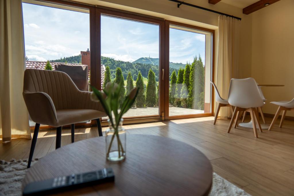 a living room with a table and a large window at Willa i Wzgórze Jerrego Apartamenty, Domki i Pokoje z Widokiem na Góry in Szczyrk