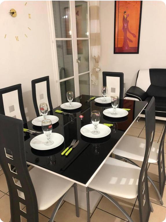 a black dining room table with white chairs and a clock at Disney golden house in Magny-le-Hongre