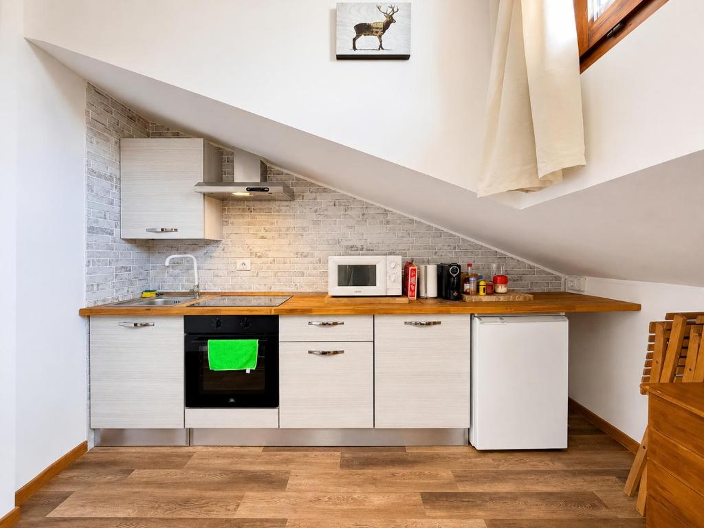 a kitchen with white cabinets and a microwave at Hostdomus - Green Valley in Borgata Sestriere