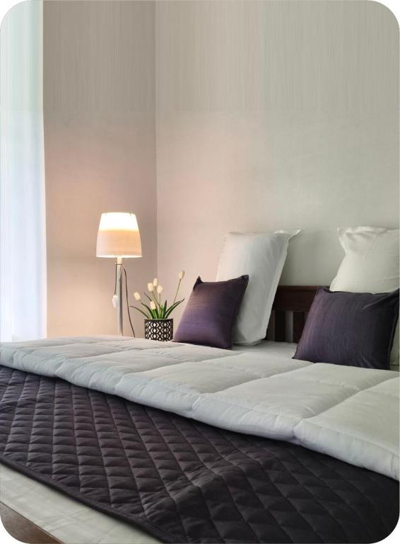 a large white bed with purple pillows and a lamp at The bharani villa in Pulpally