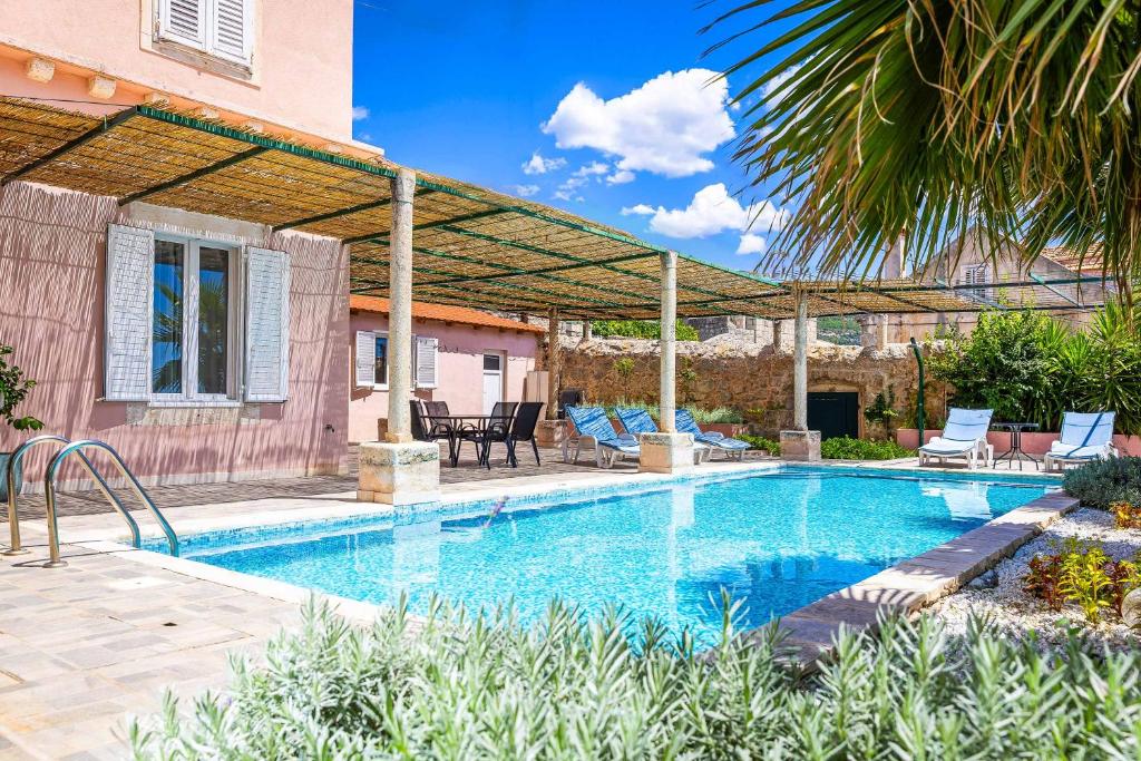 a swimming pool with a pergola next to a house at Villa Adriatic Pearl in Dubrovnik