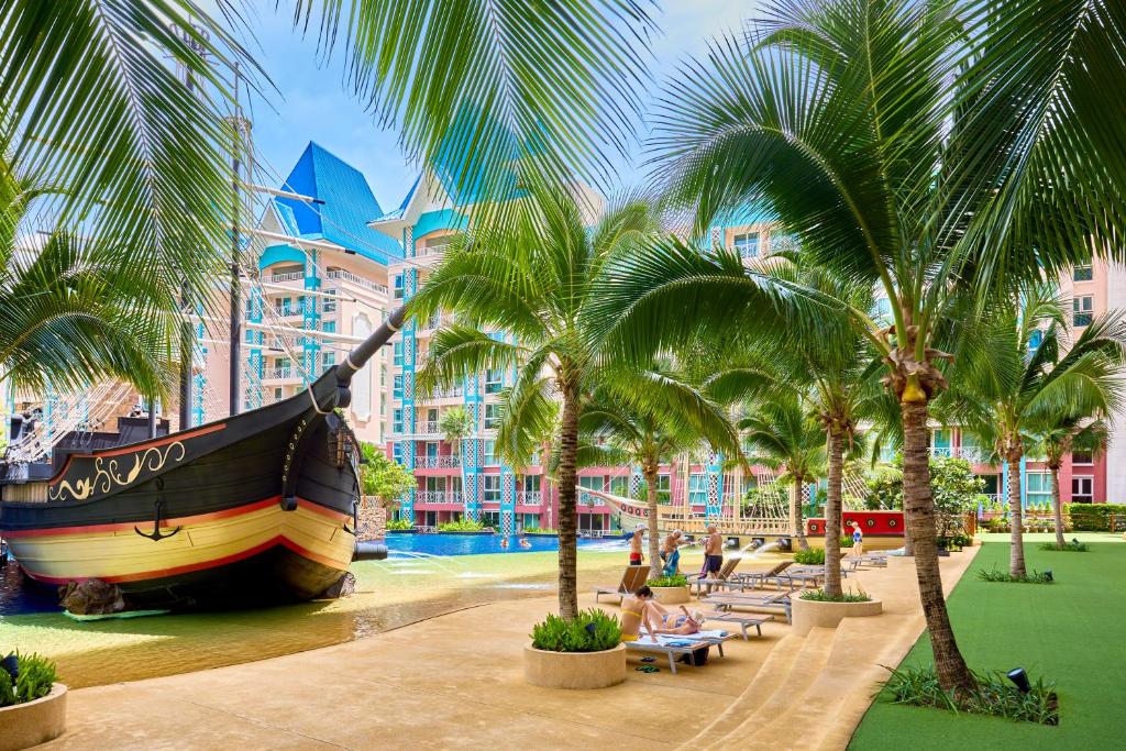 a large boat parked next to palm trees at a resort at Grande Carribean apartments Jomtien beach Pool view Sea View in Pattaya South