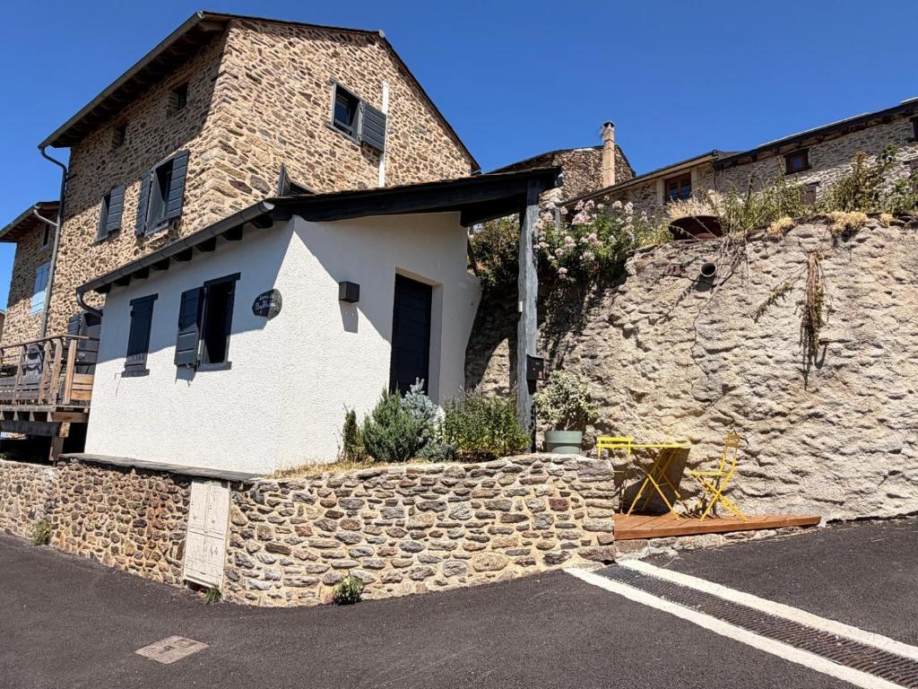 a building with a stone wall next to a street at Refuge d'Odeillo Vue lac Luxe 8 pers Les Angles in Réal