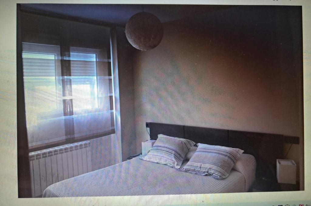a bedroom with a bed with two pillows and a window at Destino eclipse Burgo de Osma in El Burgo de Osma