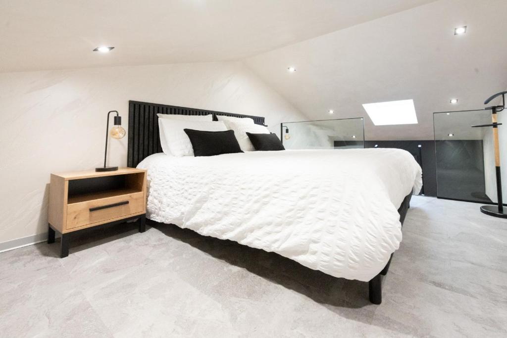 a bedroom with a large white bed and a night stand at Studio Le Saphir tout inclus petitdéjeuner in Éloyes