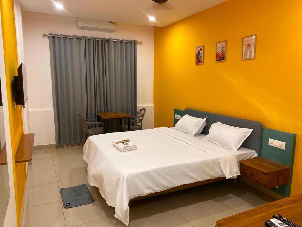 a bedroom with a bed and a yellow wall at Cozy Rooms & Dormitory in Kozhikode