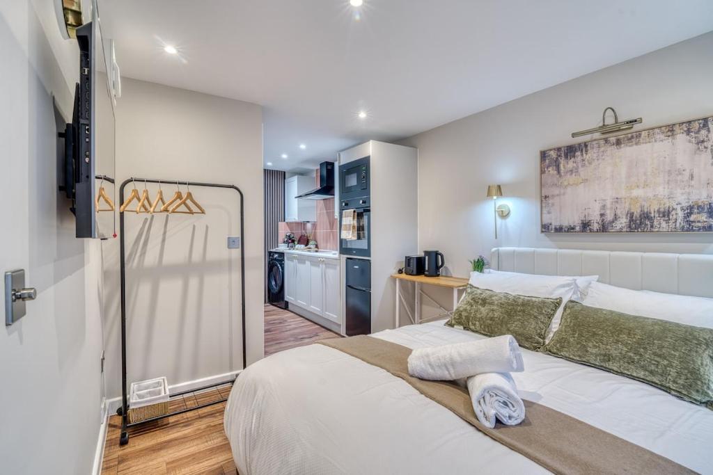 a bedroom with a large white bed and a kitchen at Cozy Studio in Eccles - Salford, Manchester in Manchester