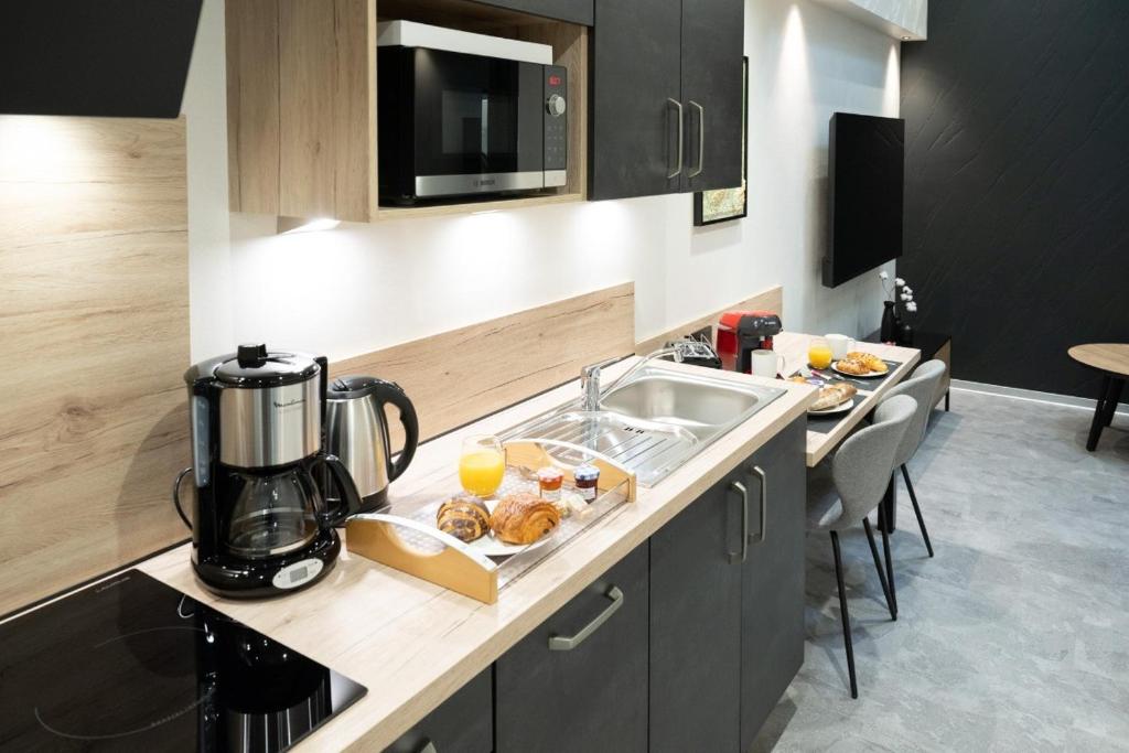 a kitchen with a sink and a counter with food on it at Studio Le Cristal tout inclus petitdéjeuner in Éloyes