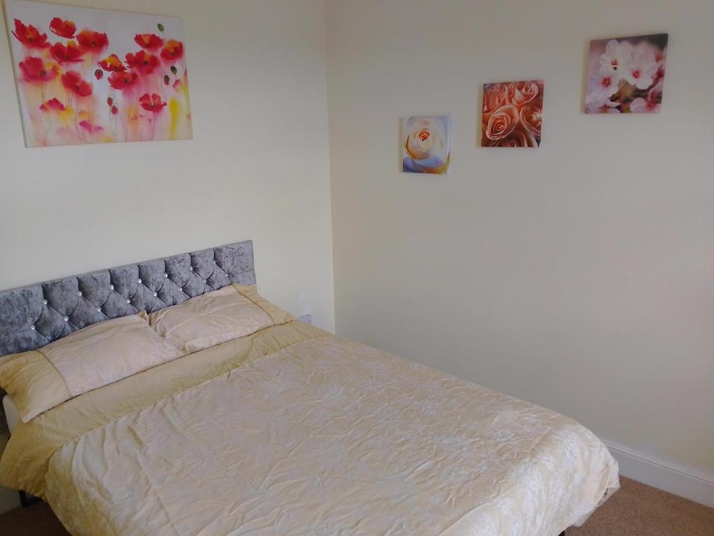 a bed in a bedroom with paintings on the wall at Nature and beach in Lowestoft