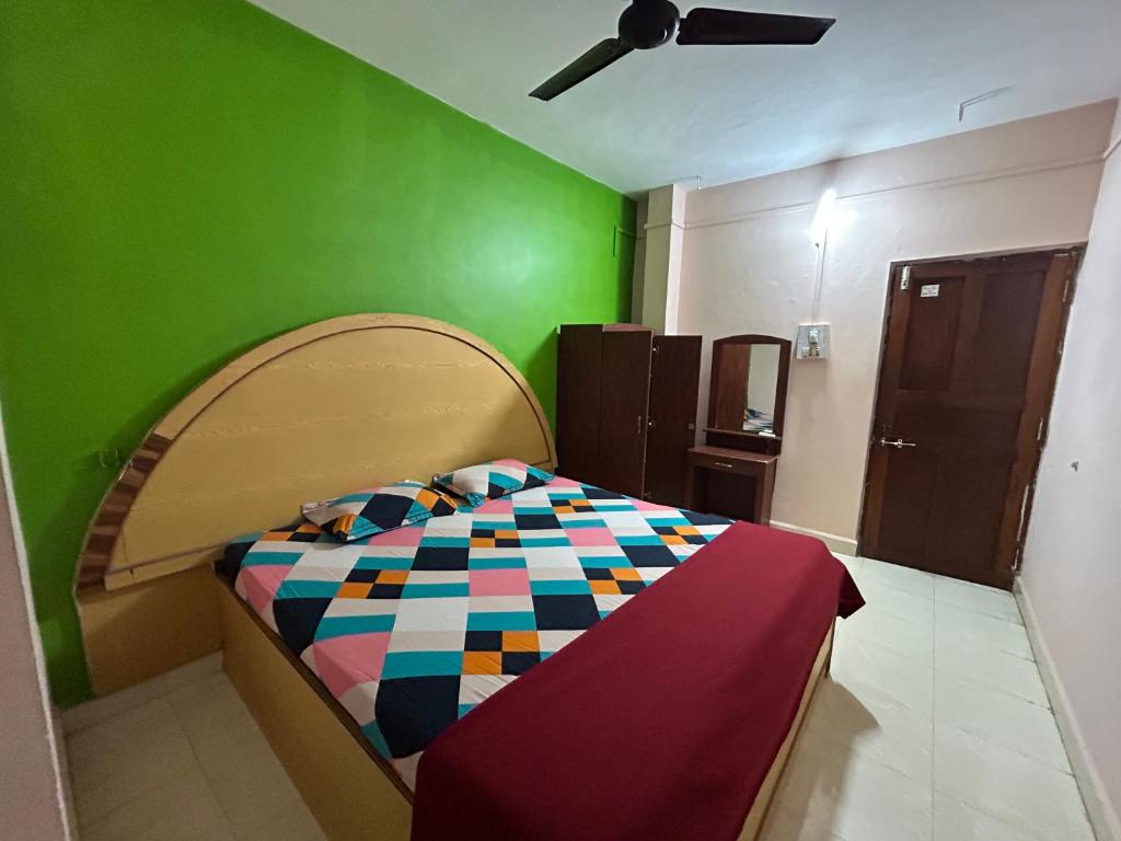 a bedroom with a bed with a green wall at Cassa ff guesthouse in Palolem