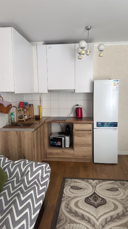 a kitchen with white cabinets and a refrigerator at Alfaresortappartmens in Koshkolʼ
