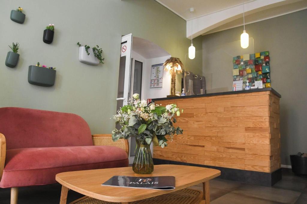a living room with a vase of flowers on a table at Hôtel Du Palais Bastia Centre in Bastia