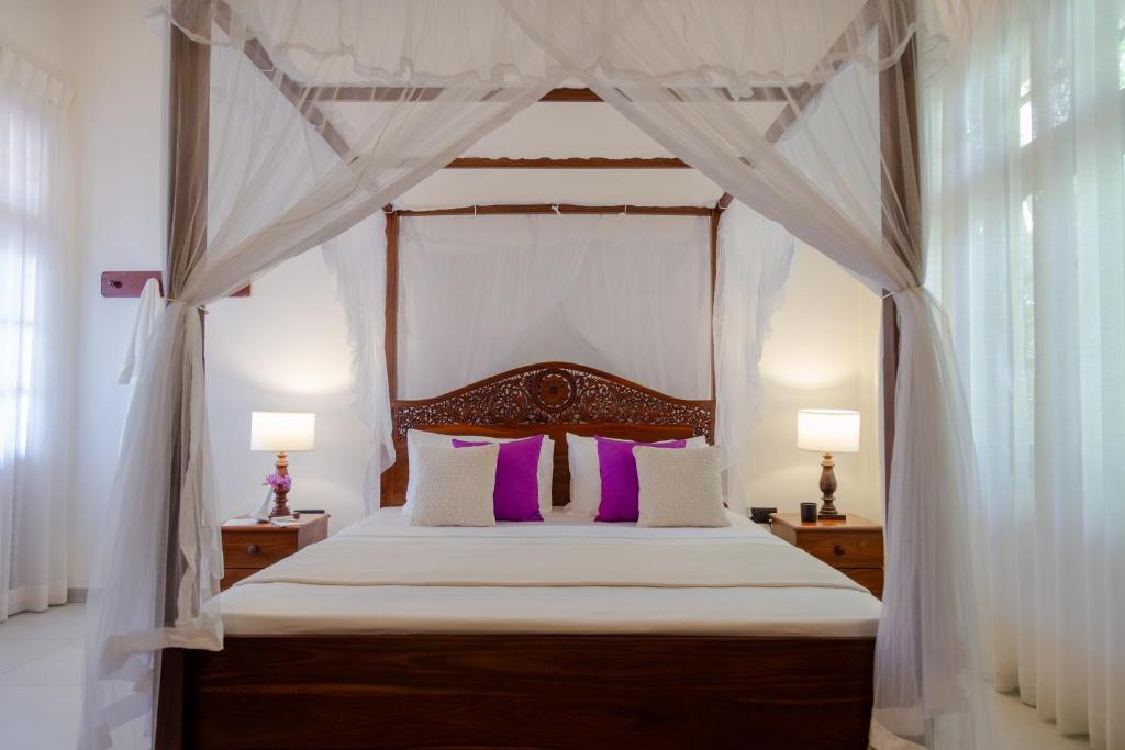 a bedroom with a canopy bed with purple pillows at Kasitha Ocean View Villa - Matara Beach Road in Matara