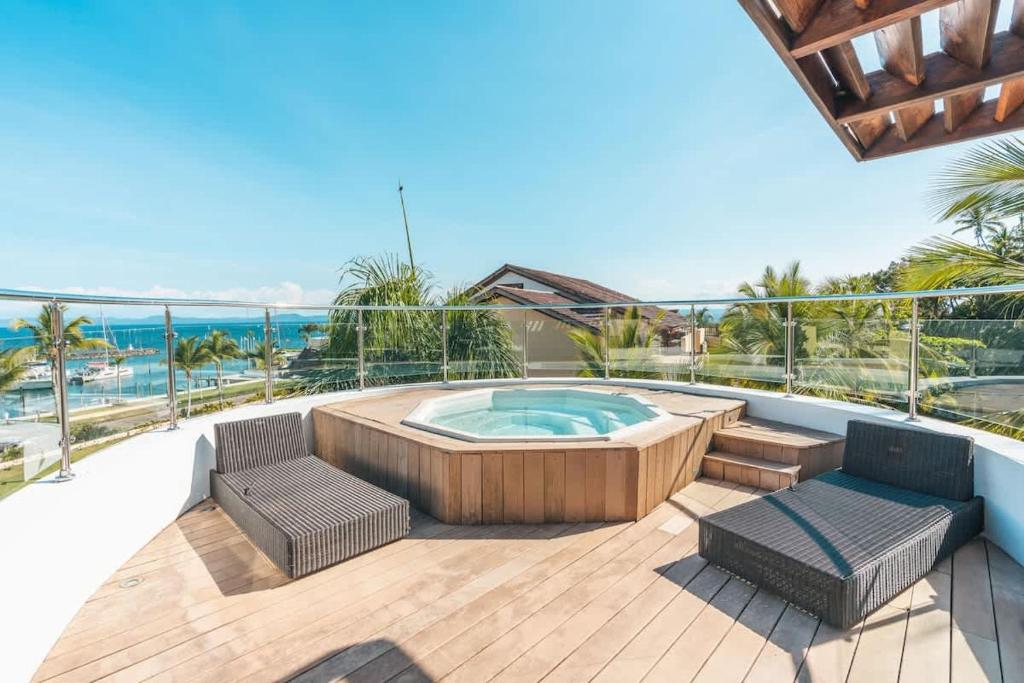 a deck with a hot tub and two chairs at Gorgeous PH at Puerto Bahia in Santa Bárbara de Samaná