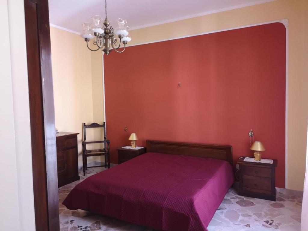 a bedroom with a bed and a red wall at Terrasini 218 in Terrasini
