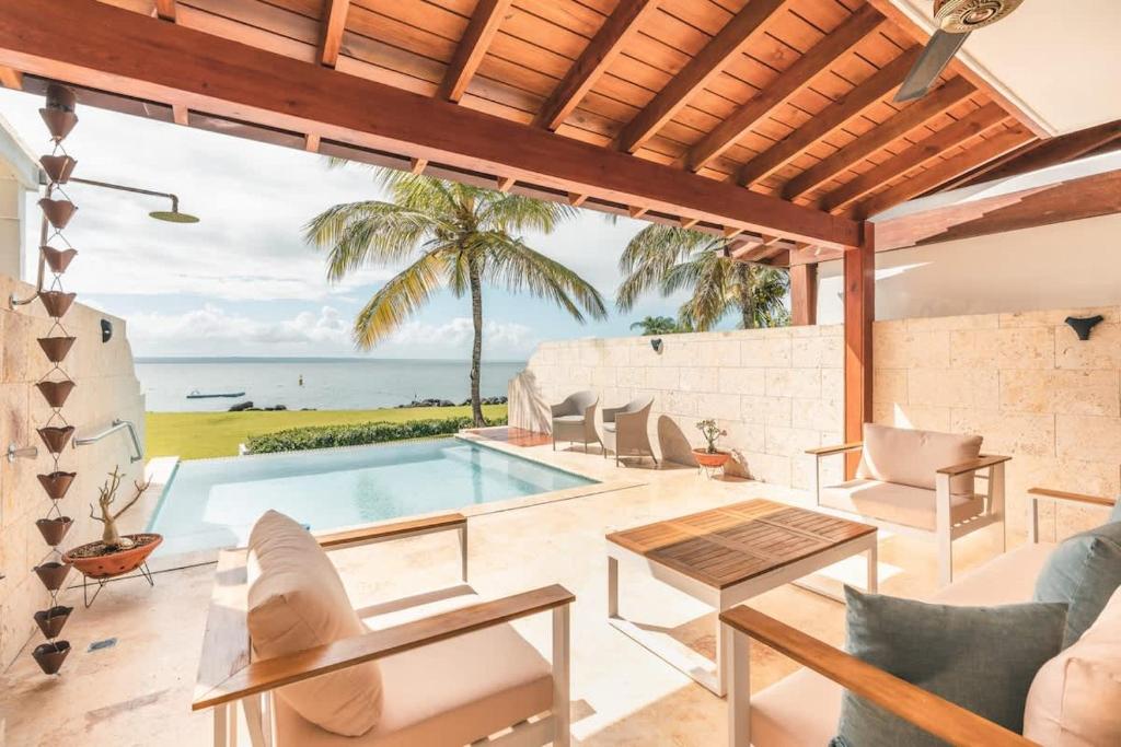 an outdoor living room with a swimming pool and the ocean at 3BR Beachfront townhouse at Puerto Bahia in Santa Bárbara de Samaná