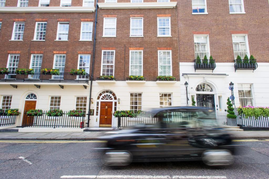 a car driving down a street in front of a building at 9 Hertford Street Mayfair in London
