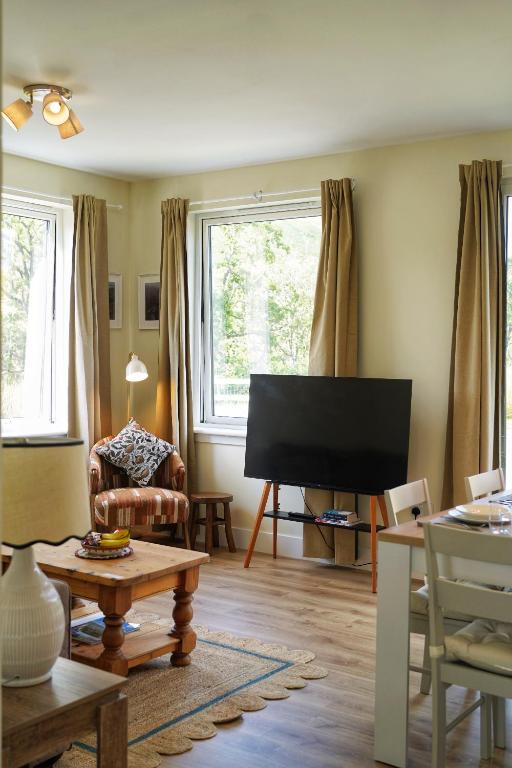a living room with a flat screen tv and a chair at Auch - Cottages in Bridge of Orchy