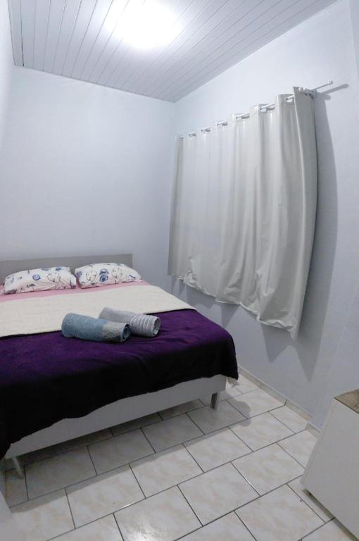 a bedroom with a bed with a purple blanket at Pousada familiar 07 in Rio do Sul