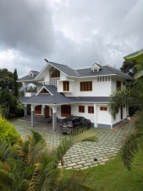 a white house with a car parked in the driveway at Bamivigas Retreat in Kattappana