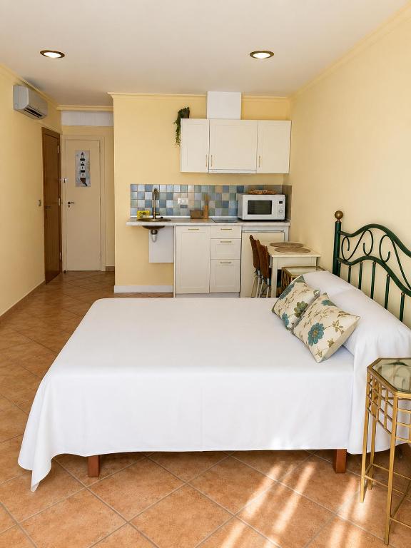 a bedroom with a large white bed and a kitchen at Holibai Misiño, Estudio para dos en Baiona in Baiona
