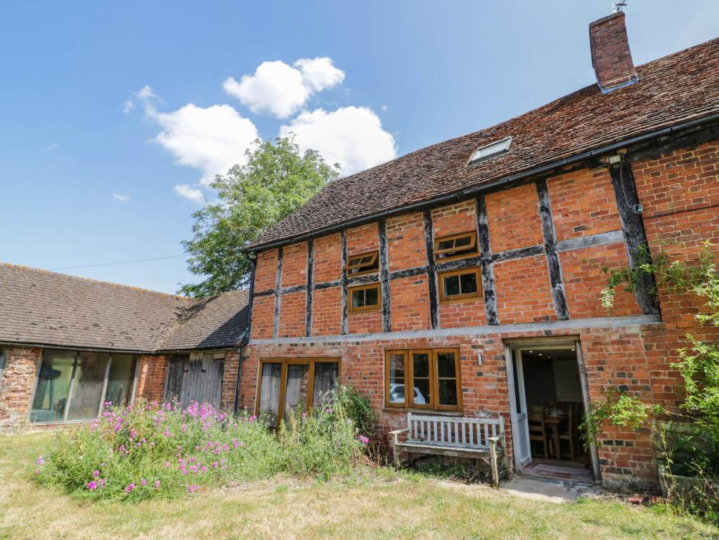 an old brick building with a bench in front of it at Netherend Barn in Colwall