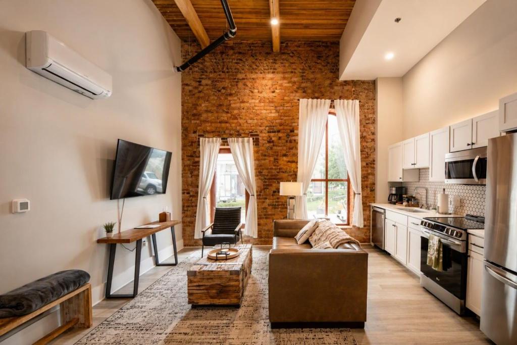 ein Wohnzimmer mit einer Couch und einer Backsteinwand in der Unterkunft Three Trails Downtown Elkin in Elkin