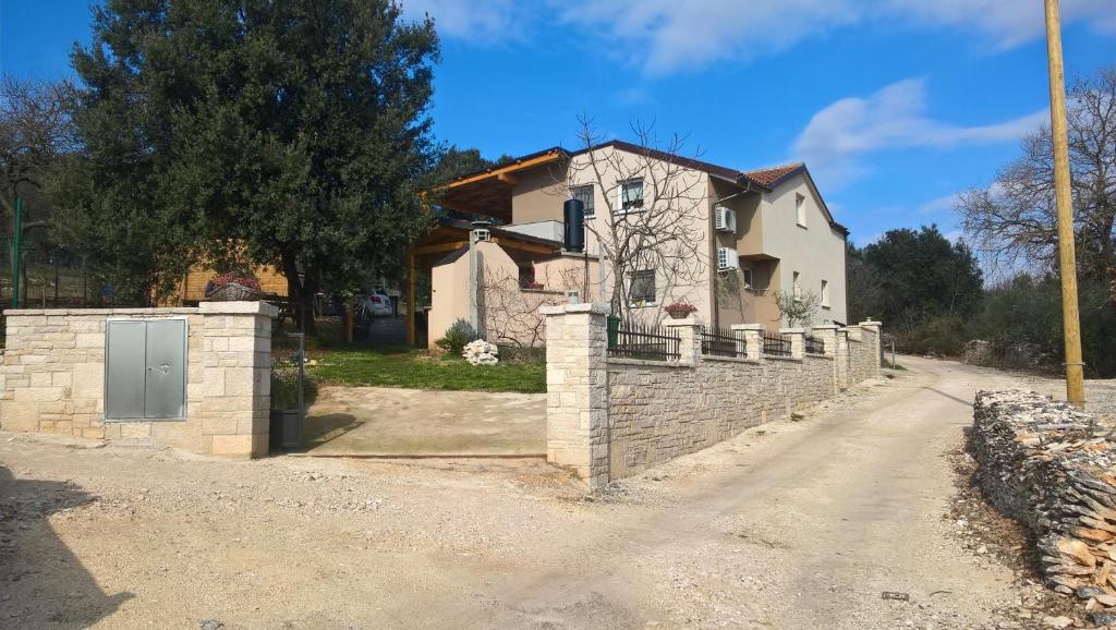 a house with a stone fence next to a road at Apartments Salak in Pula