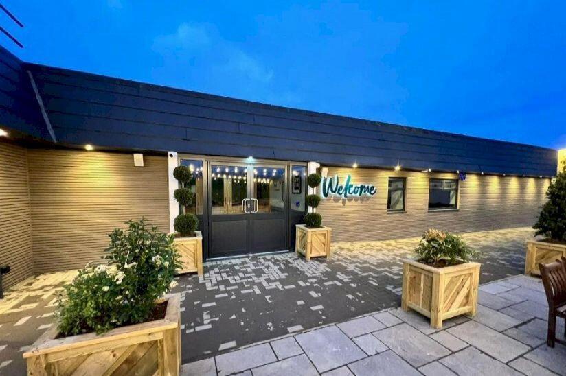 a building with a door with a sign on it at Glendale Holiday Park in Wigton