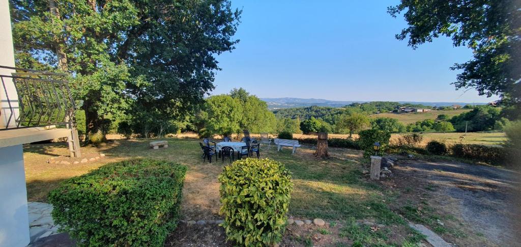 a garden with a table and chairs and trees at Rosabelle in Beaulieu-sur-Dordogne