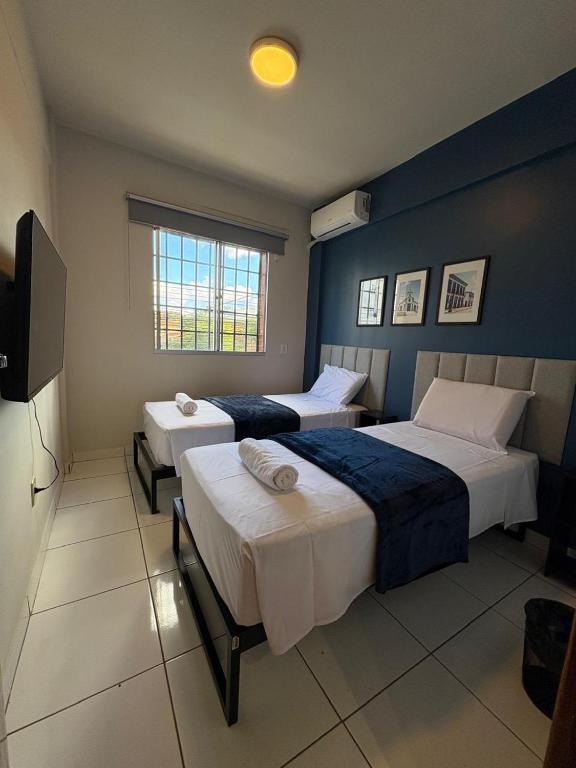 a hotel room with two beds and a television at Quarto com Ar Condicionado e banheiro no centro in Montes Claros