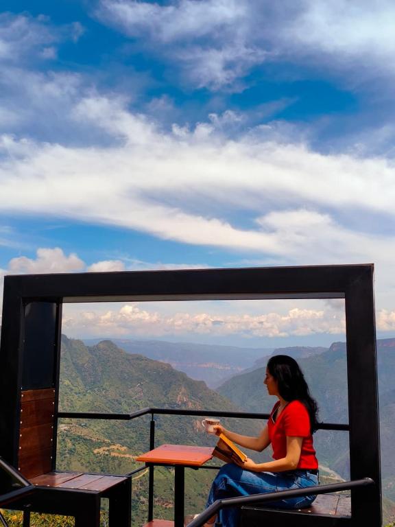a woman sitting at a table on top of a mountain at Cabañas Cañon Del Chicamocha in Aratoca