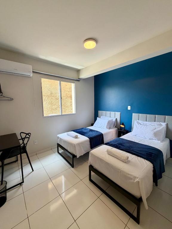 a bedroom with two beds and a blue wall at Apto com 2 quartos e A/C ao lado da Santa Casa in Montes Claros