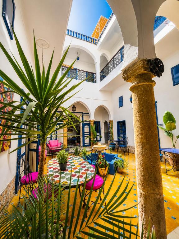 a room with a table and chairs and a palm tree at Riad Safi - maison historique in Safi