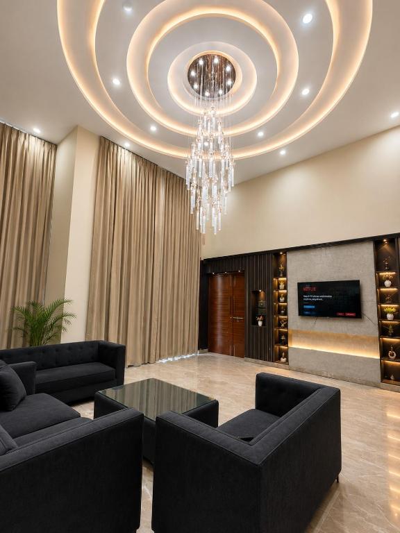 a living room with a chandelier and black furniture at Hotel Del Luna in Greater Noida