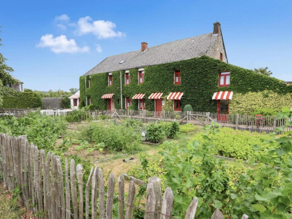 a house covered in ivy with a fence at Ferme de la Galoperie in Couvin