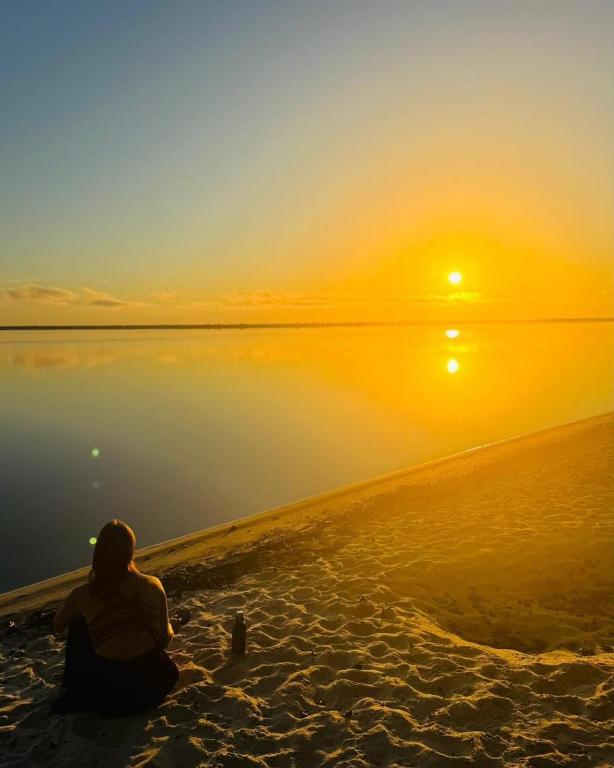 a person sitting on the beach watching the sunset at Praia Grande Ecolodge in Manacapuru