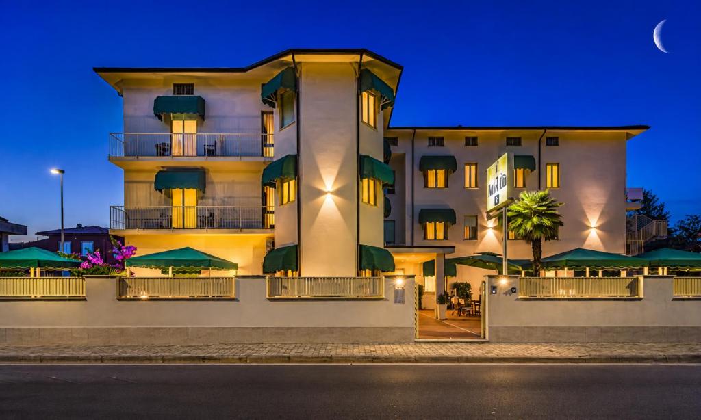 a large building with green umbrellas in front of it at Hotel Liu in Lido di Camaiore